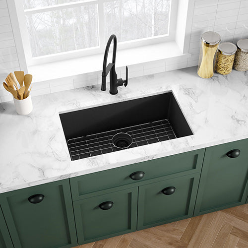 The elegant fusion of a black faucet and kitchen sink, complemented by a grid pattern, enhances the aesthetic appeal of the kitchen, especially against the backdrop of charming green cabinetry.