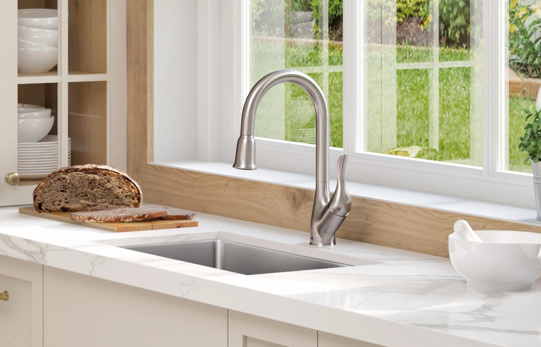 French bread sitting right next to a beautiful faucet which mounted on a stainless steel sink in a kitchen